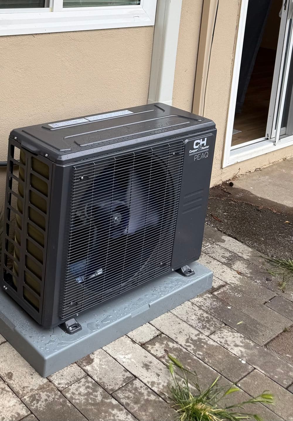 Air conditioning unit installed outside a home on a concrete base. Energy-efficient cooling solution.